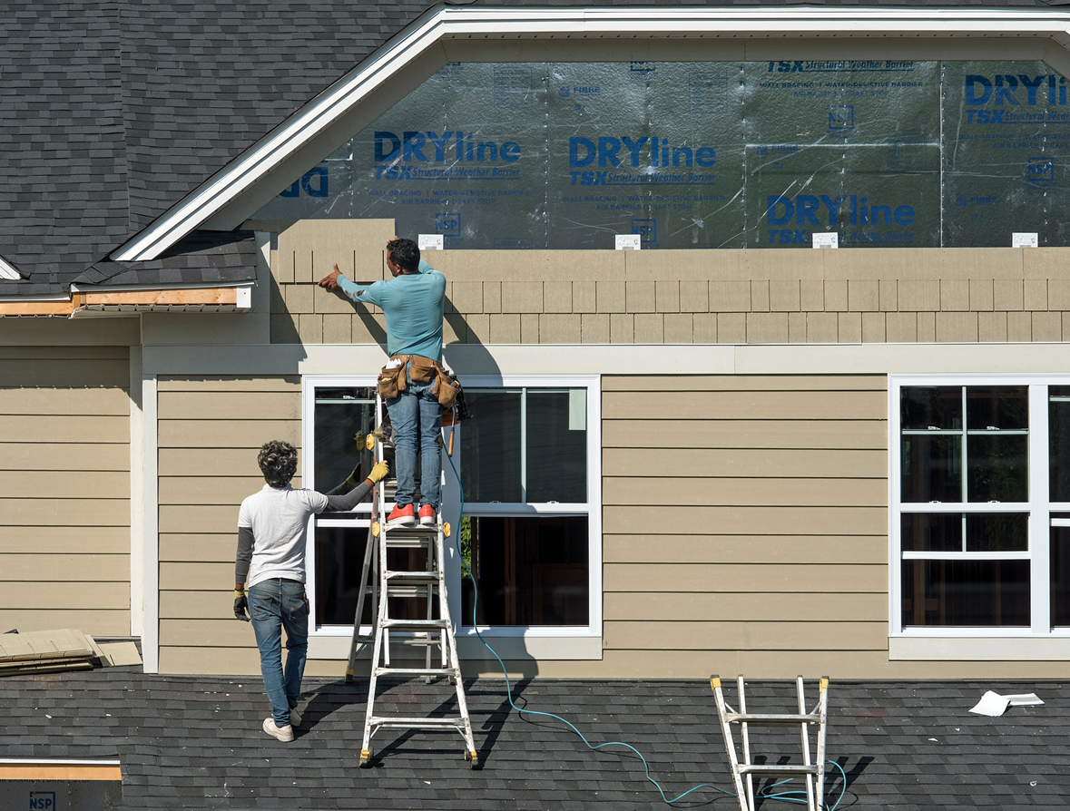 Construction workers installing house siding