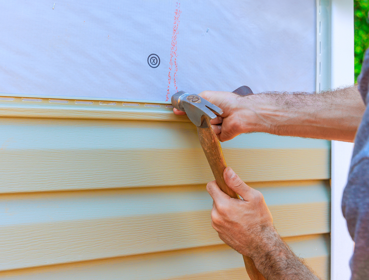 Worker attaching siding to exterior wall