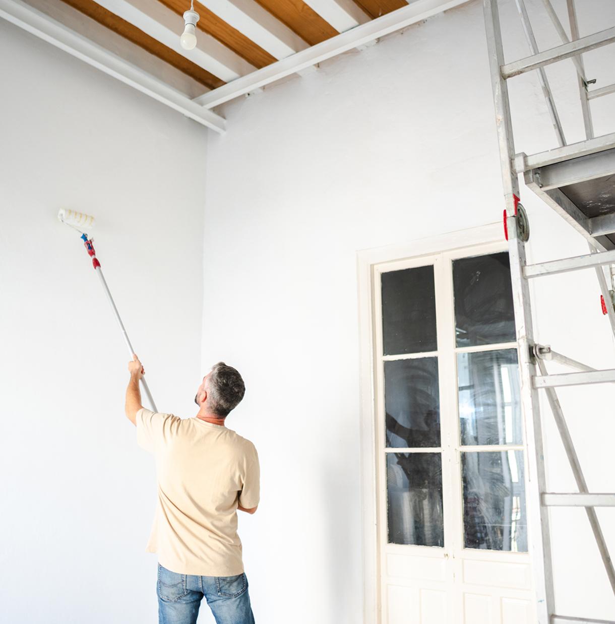 Man painting a high wall white