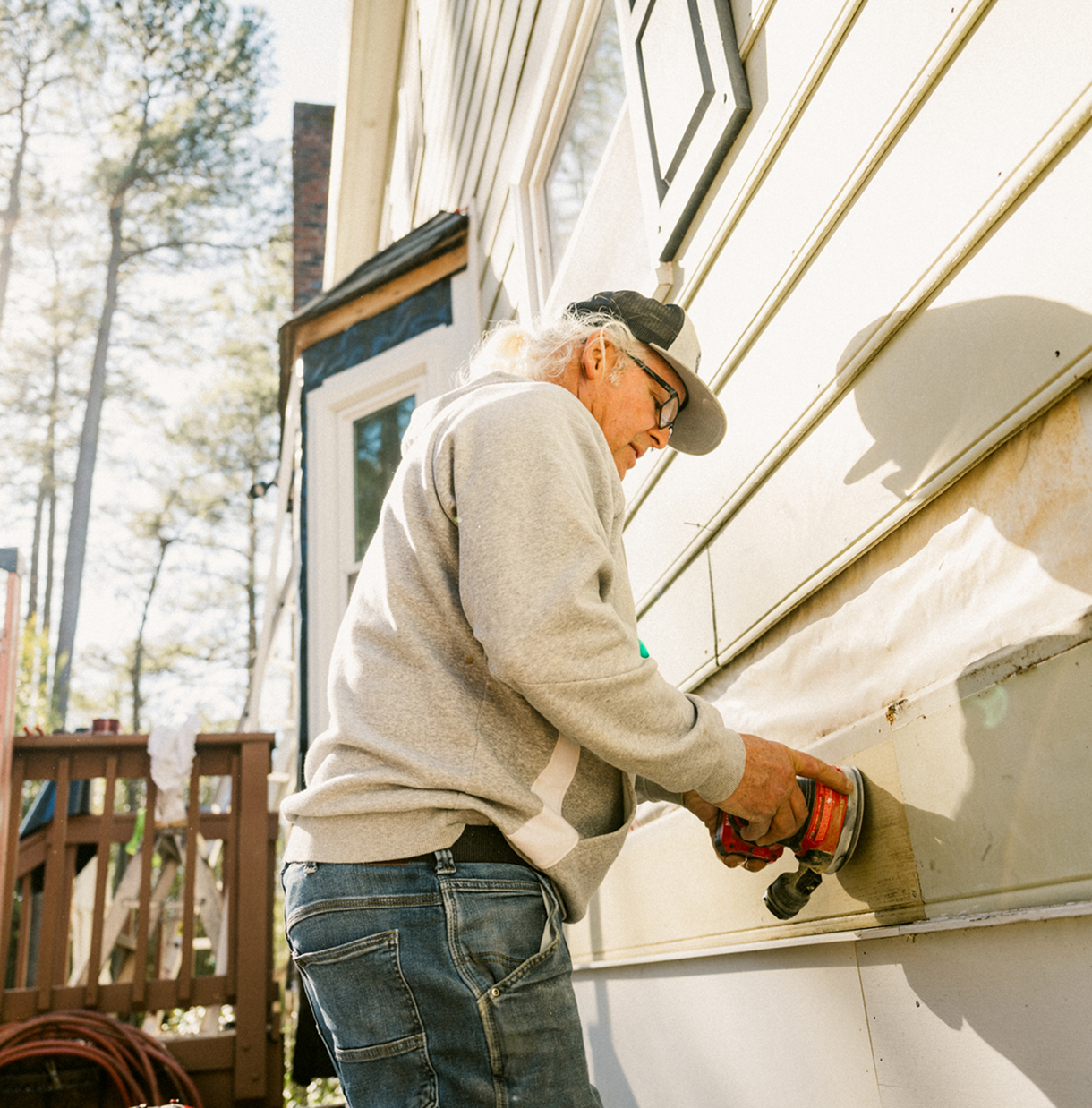 Man using power tool on house siding.