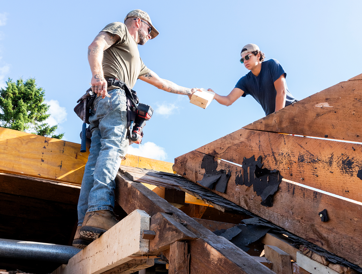 Construction workers handing materials on roof