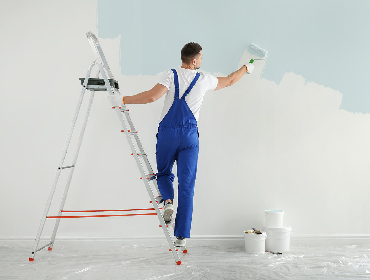Man painting wall with blue paint