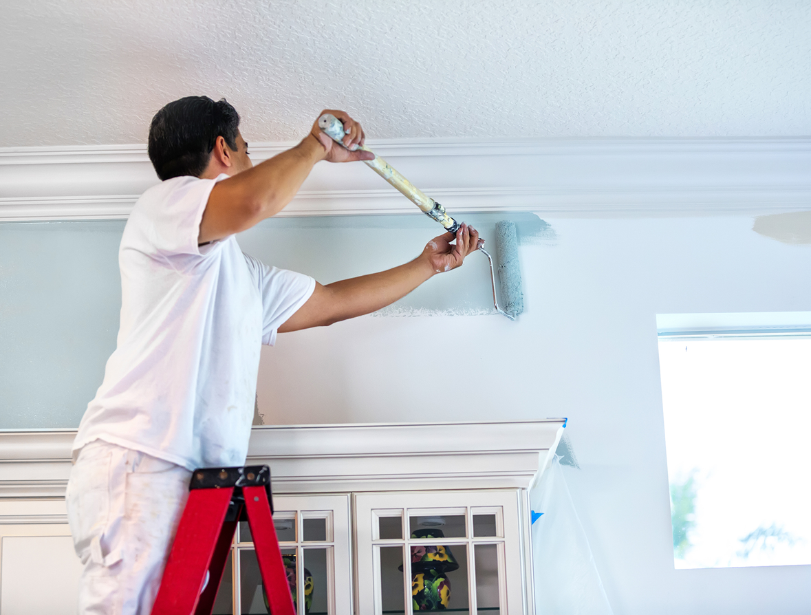 Painter applying blue paint to wall